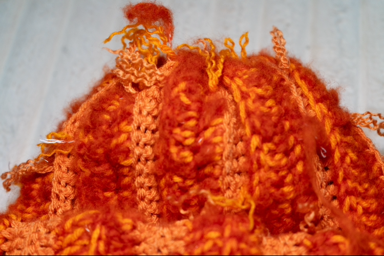 Crocheted orange hat on a white surface
