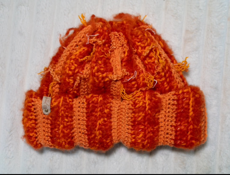 Crochet orange hat on a textured white background